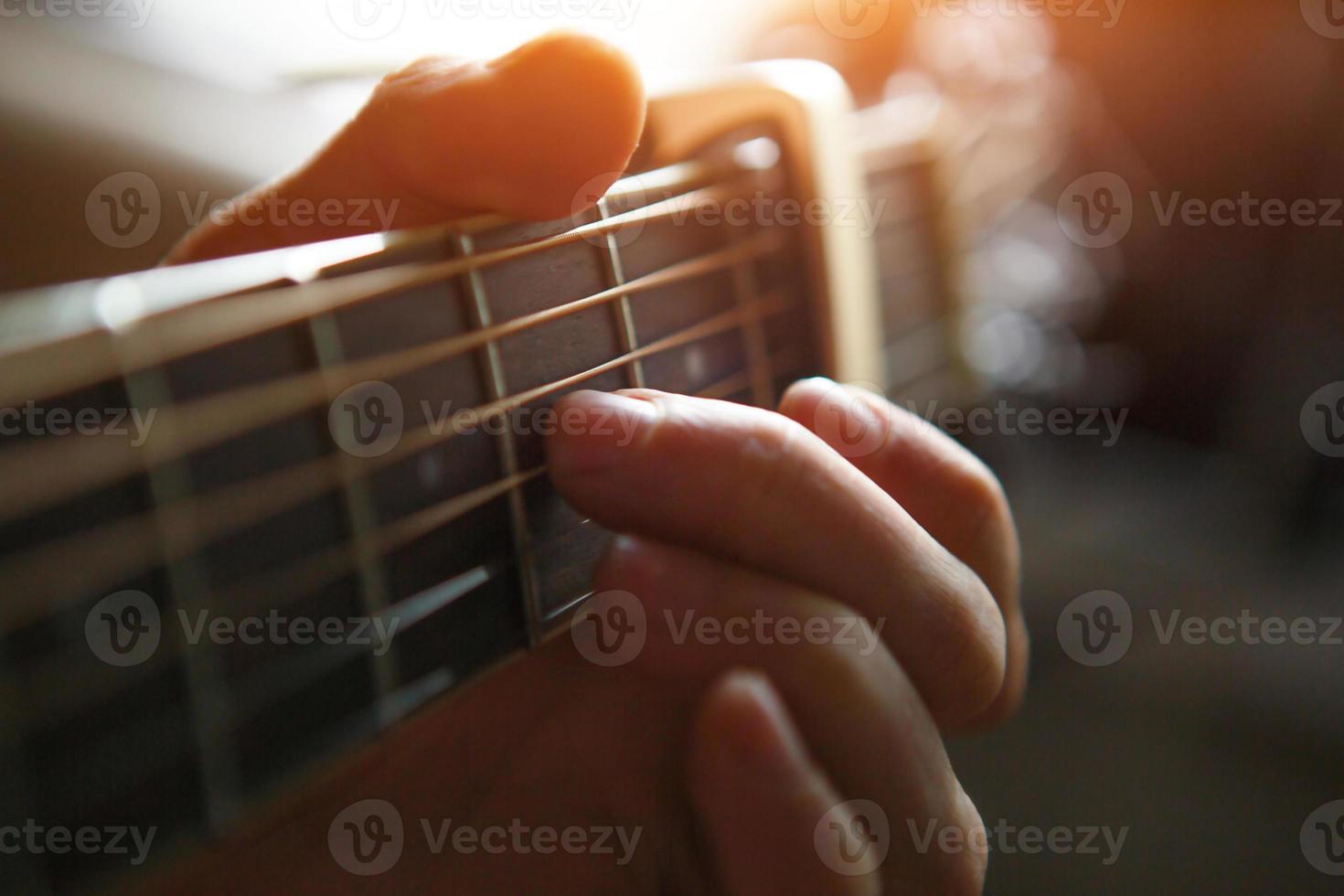 A man's hand on the fretboard of a guitar runs his fingers through the strings and clamps the chords. Instrumental music, guitar lesson on sheet music photo