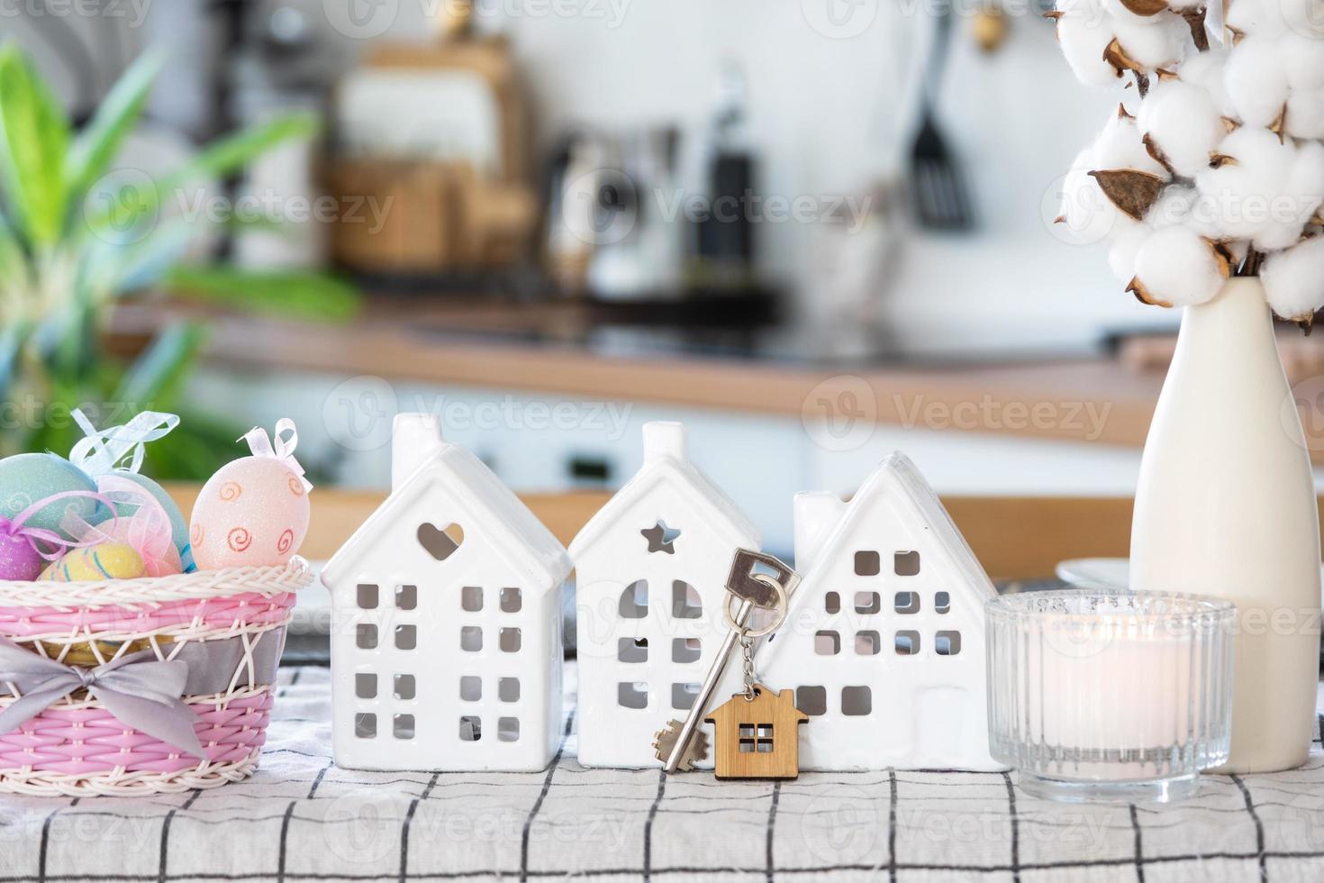 Key to house of cozy home with Easter decor with rabbit and eggs on table of kitchen. Building, design, project, moving to new house, mortgage, insurance, rent and purchase real estate photo