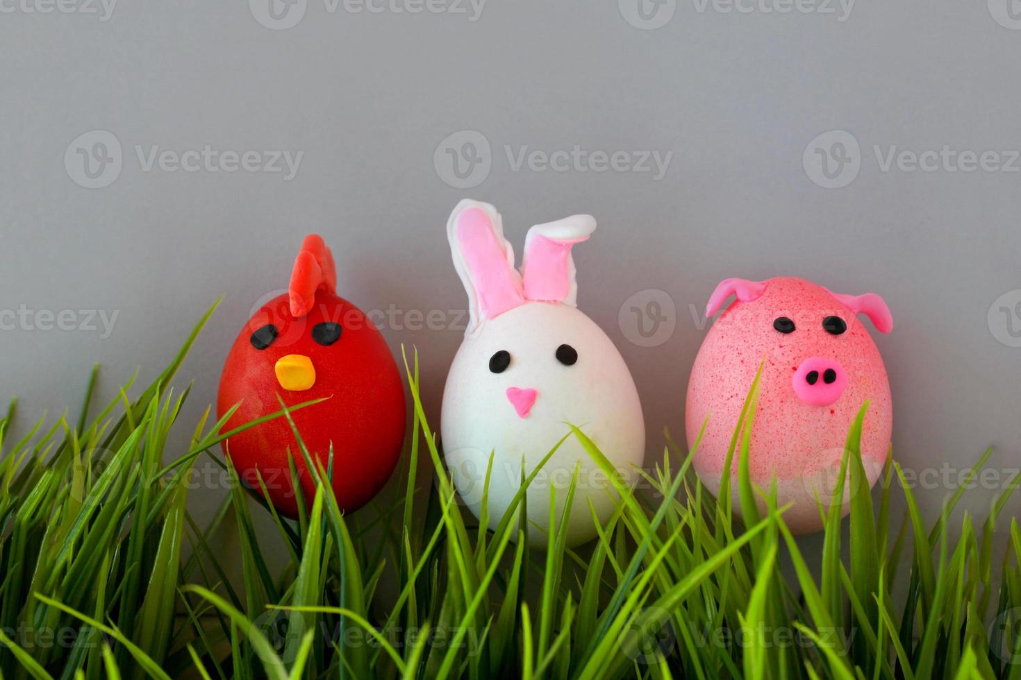 Easter holiday, a handmade egg made by a child in the form of a rabbit , chicken  and pig against a grey background. photo