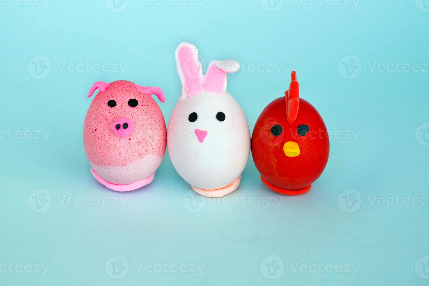 Easter holiday, a handmade egg made by a child in the form of a rabbit , chicken  and pig against a blue background. photo