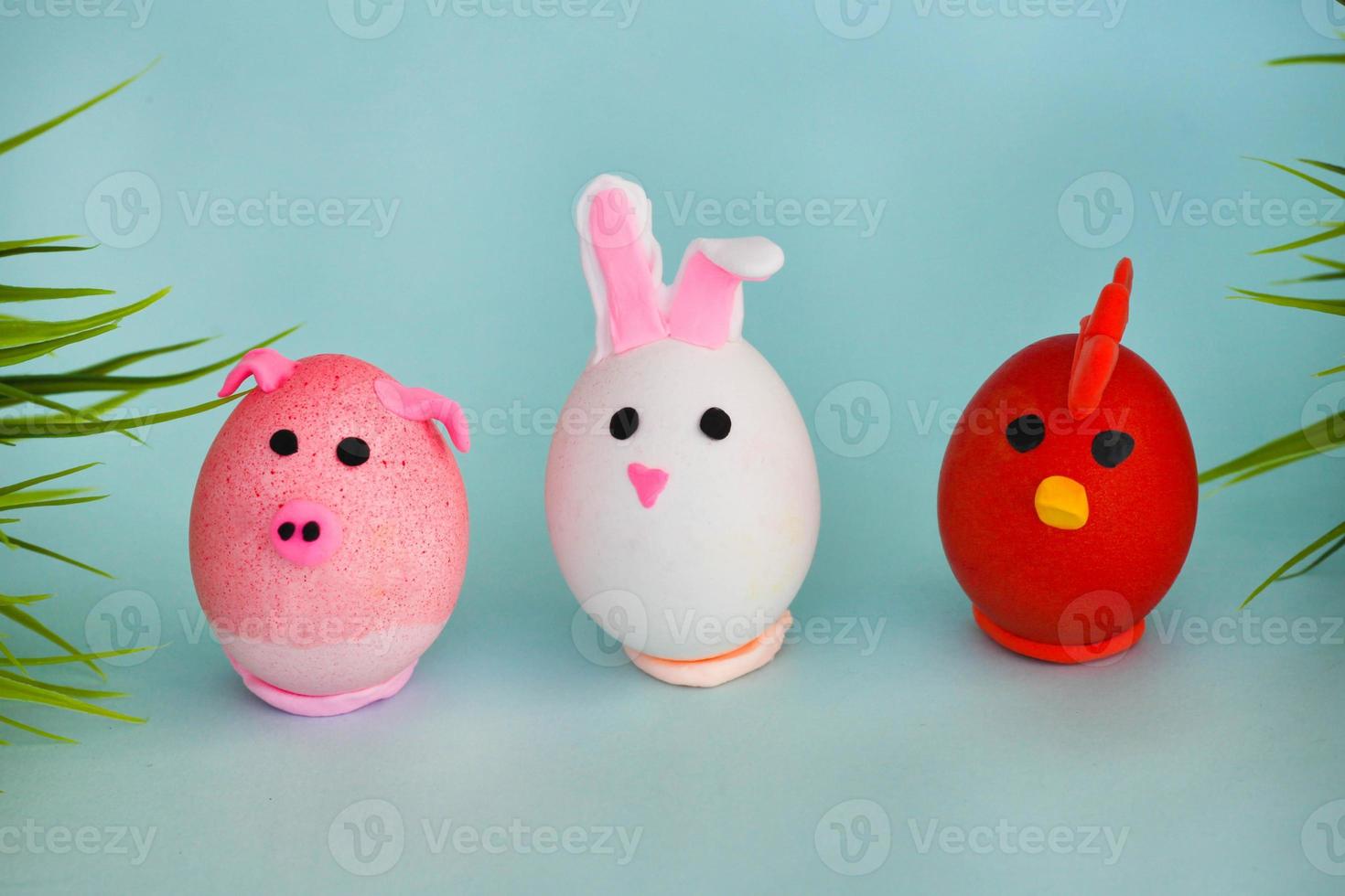 Easter holiday, a handmade egg made by a child in the form of a rabbit , chicken  and pig against a blue background. photo