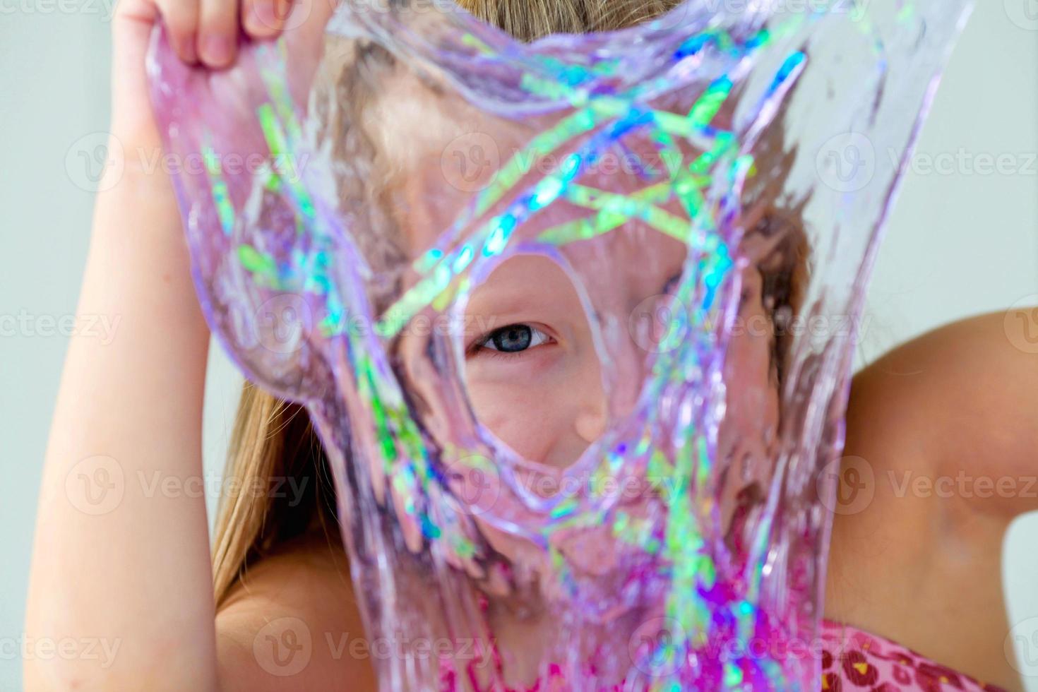 Funny girl holdin a slime in front of her face and looking through its hole. photo