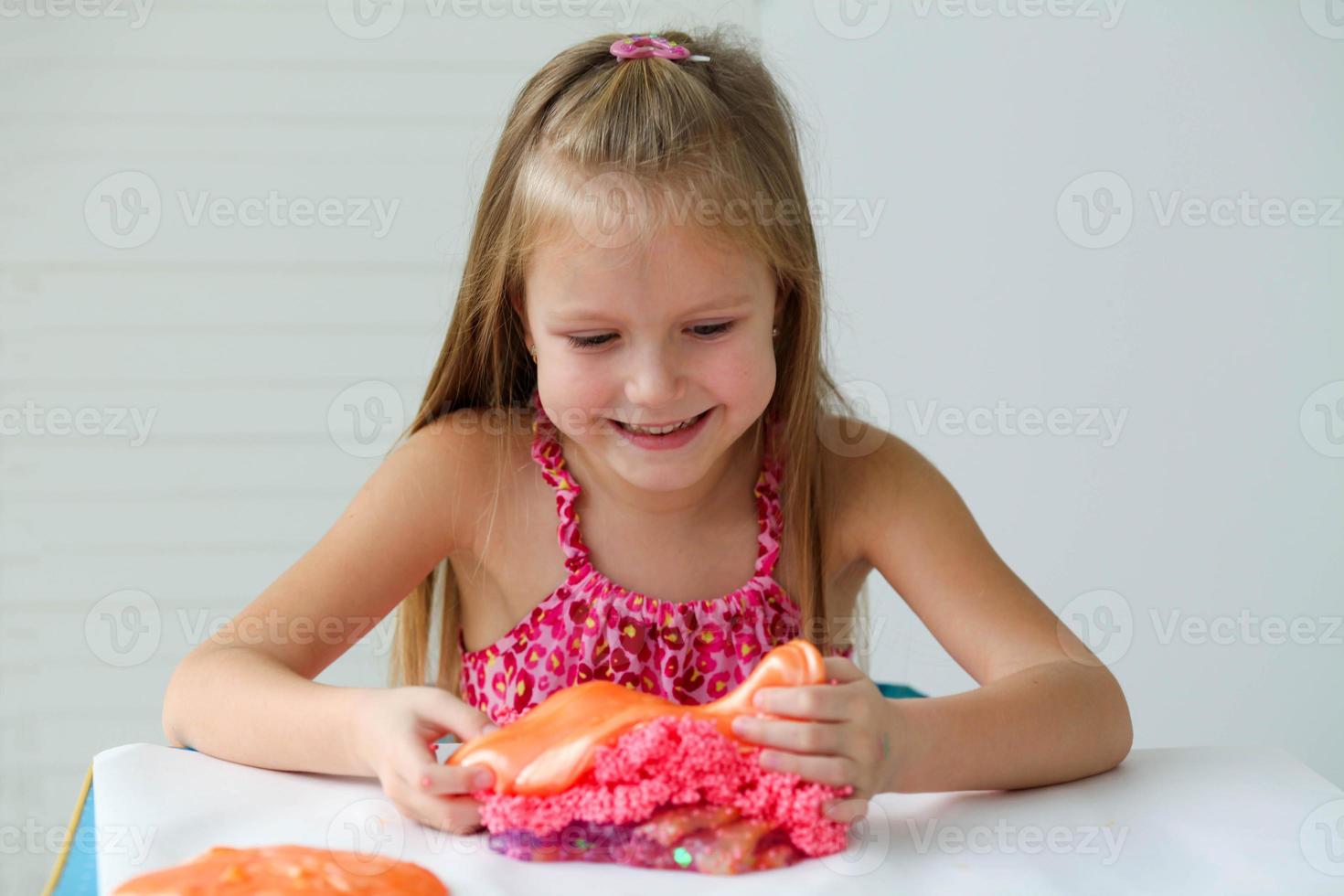 Girl playing hand made toy called slime.Slime, kids having fun and being creative by science experiment. A child mixes several slimes into one photo