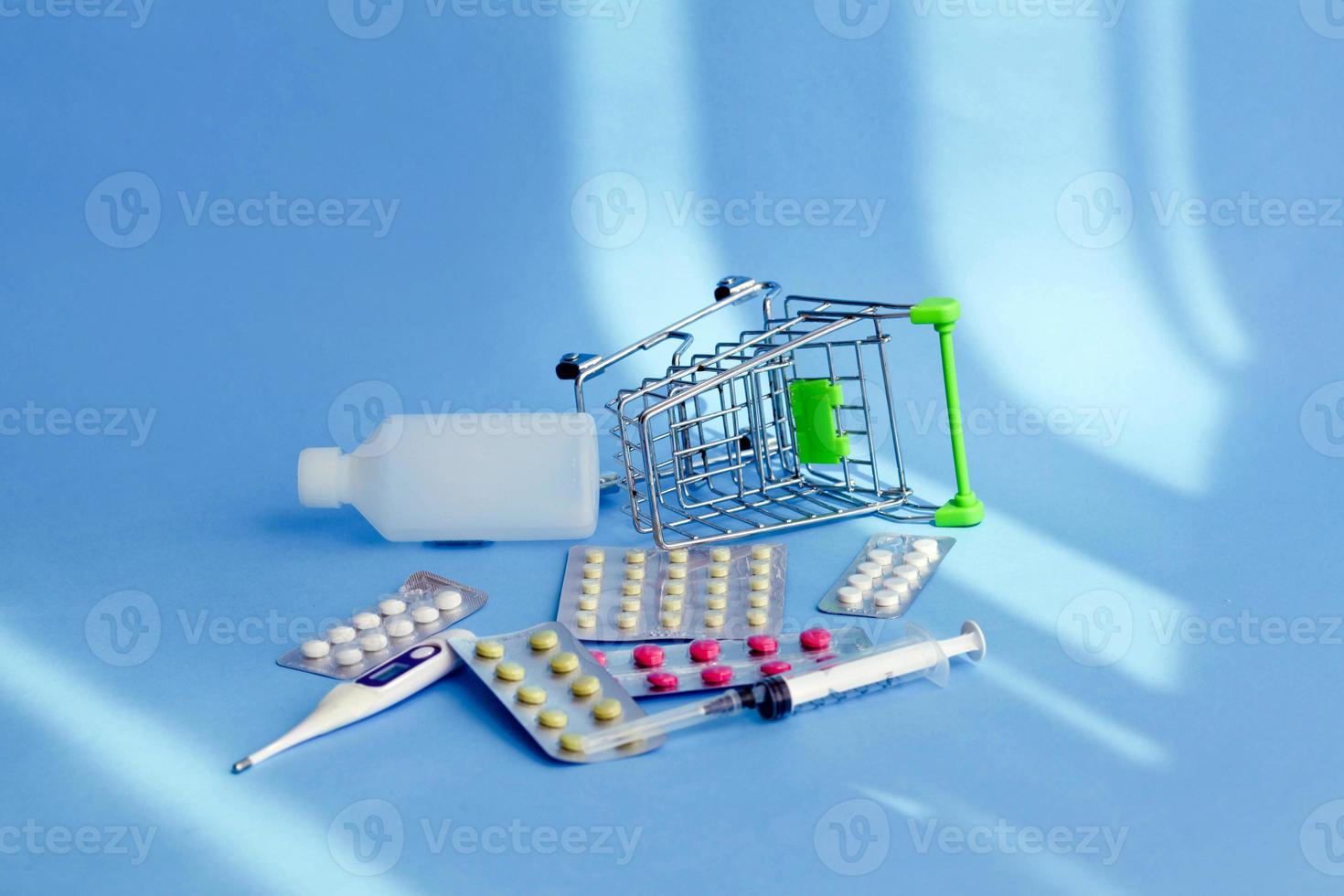 Shopping cart full of medical pills ,thermometer and medicine fell down with medical drugs spilled over the floor.Consumer buying panic about coronavirus covid-19 concept. photo