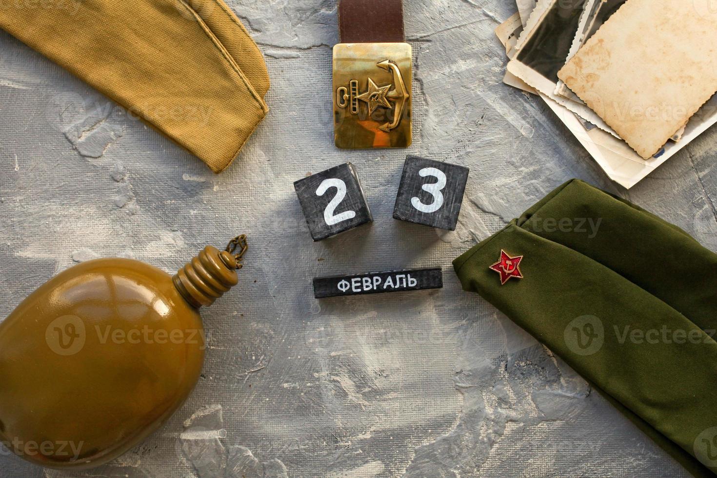 Flask, cap, soldier's military belt, old photographs of the war years and a wooden calendar with the date February 23. photo