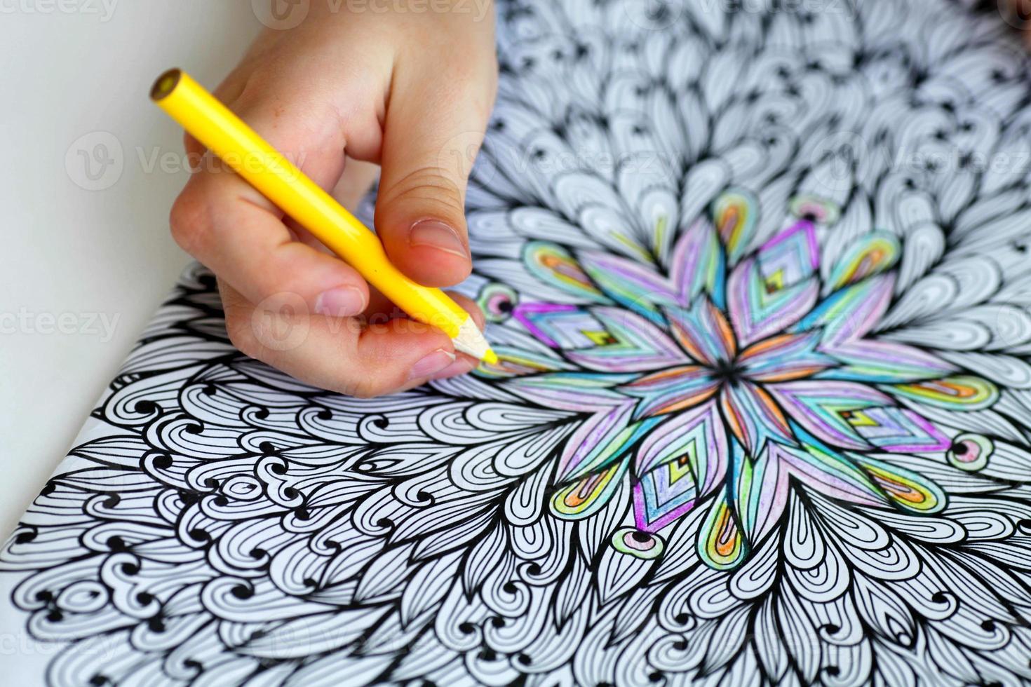 Close-up of girls hands draw with crayons in antistress coloring. photo