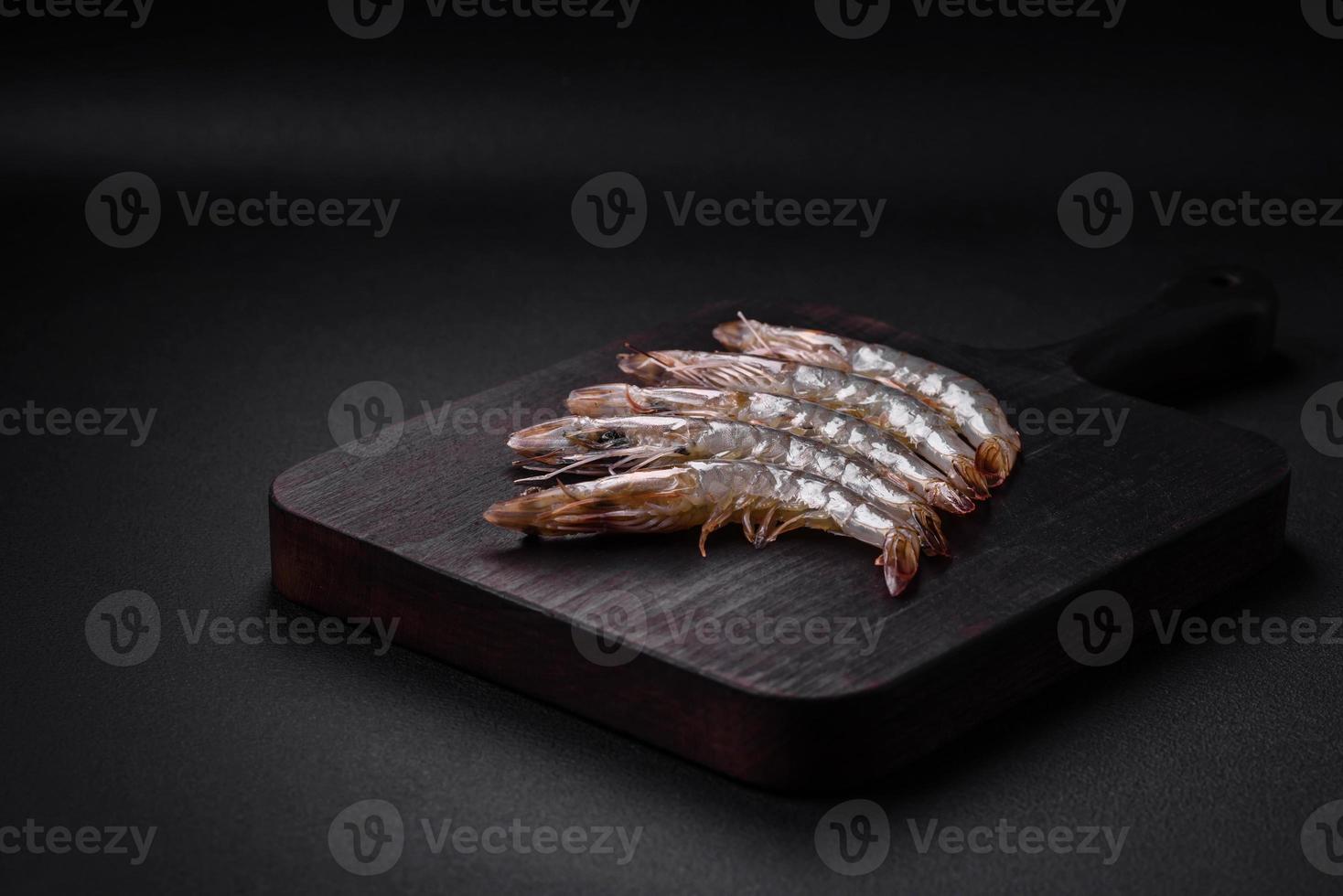 Tiger prawn or langoustine raw with spices and salt on a wooden cutting board photo