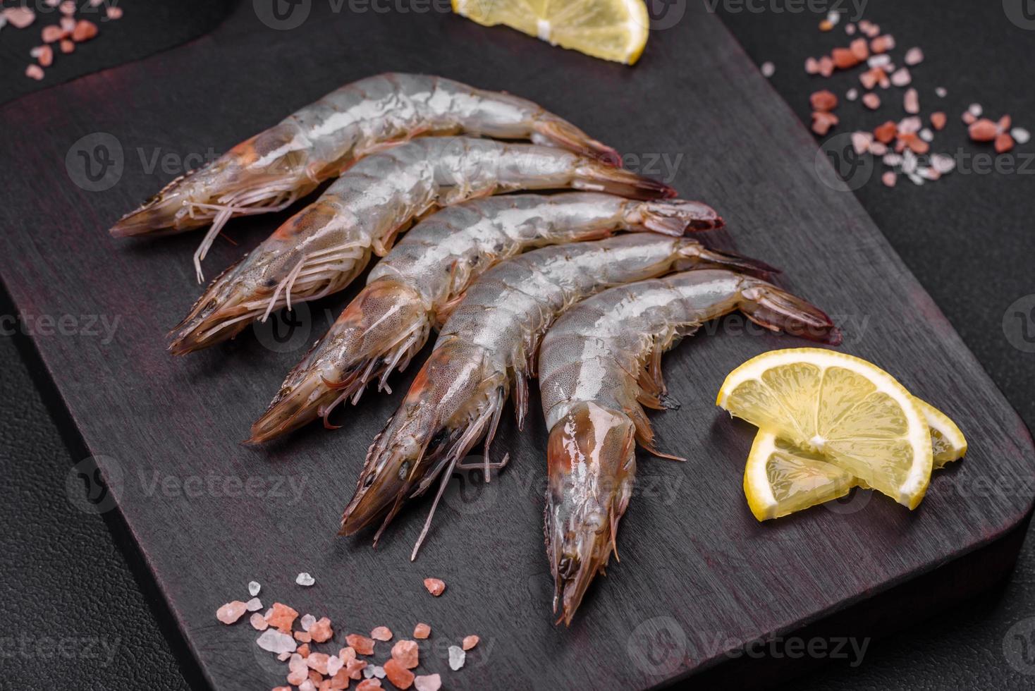 Tigre gamba o langostinos crudo con especias y sal en un de madera corte tablero foto