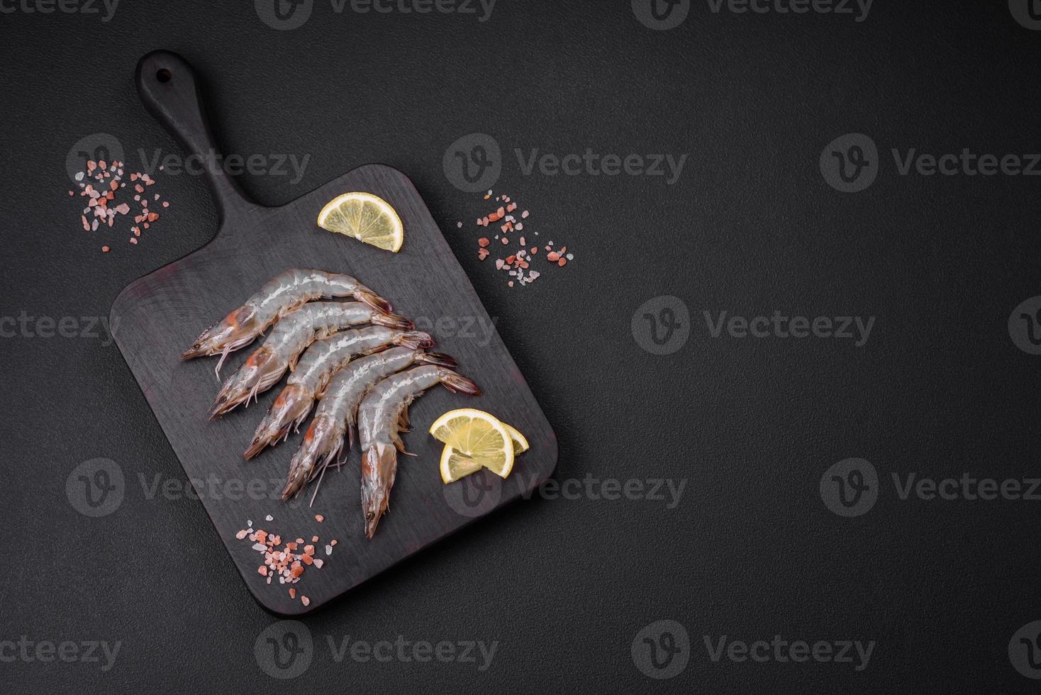 Tiger prawn or langoustine raw with spices and salt on a wooden cutting board photo