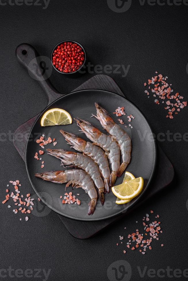 Tiger prawn or langoustine raw with spices and salt on a wooden cutting board photo