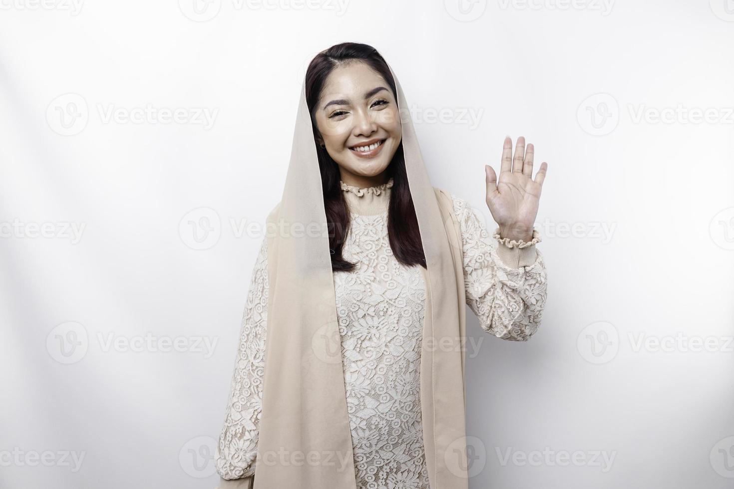 Portrait of a young beautiful Asian Muslim woman wearing a headscarf gesturing Eid Mubarak greeting photo