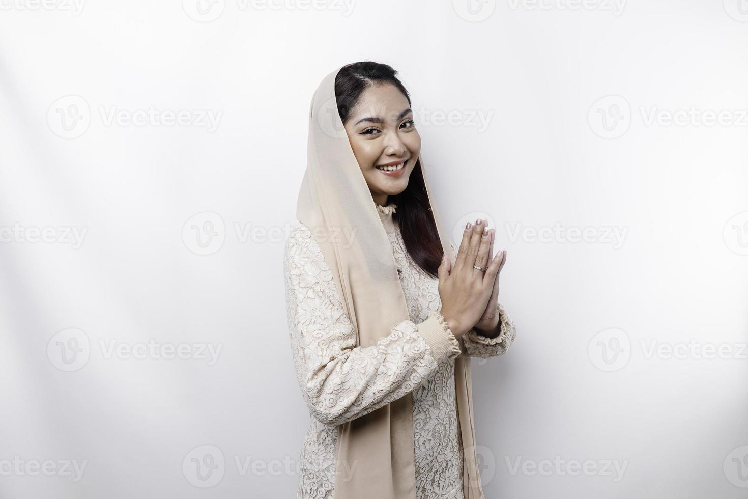 Portrait of a young beautiful Asian Muslim woman wearing a headscarf gesturing Eid Mubarak greeting photo