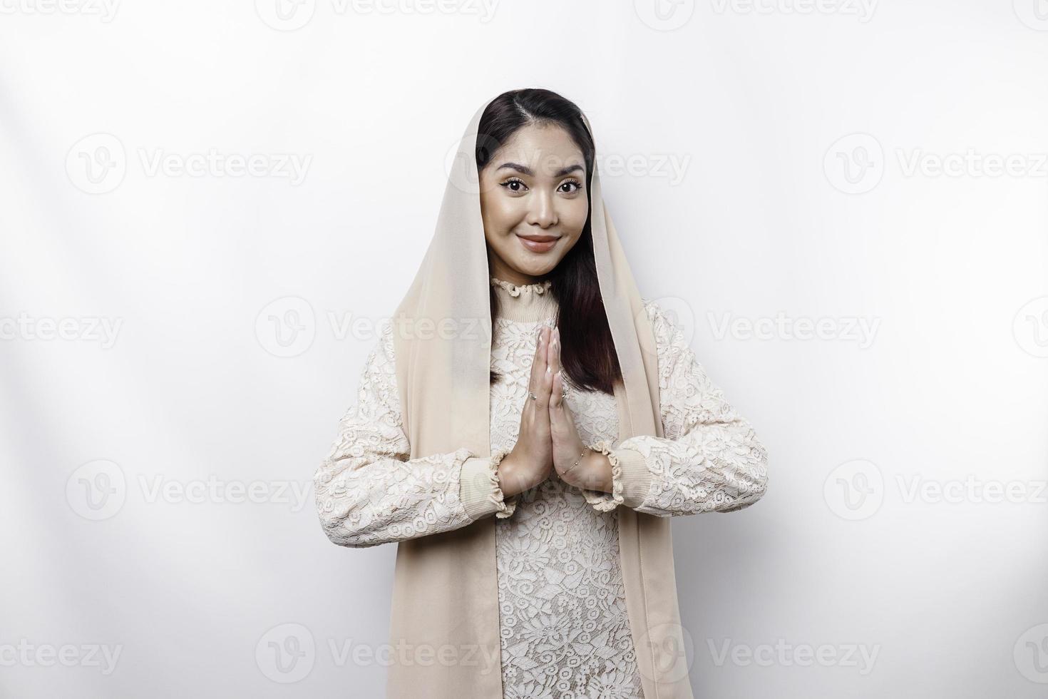 Portrait of a young beautiful Asian Muslim woman wearing a headscarf gesturing Eid Mubarak greeting photo