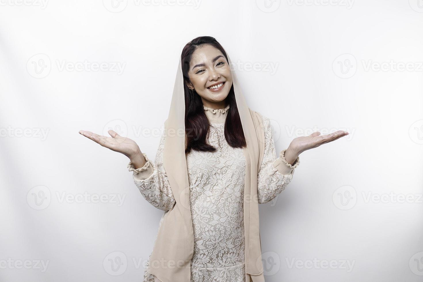 Young Asian Muslim woman smiling while pointing to copy space beside her photo