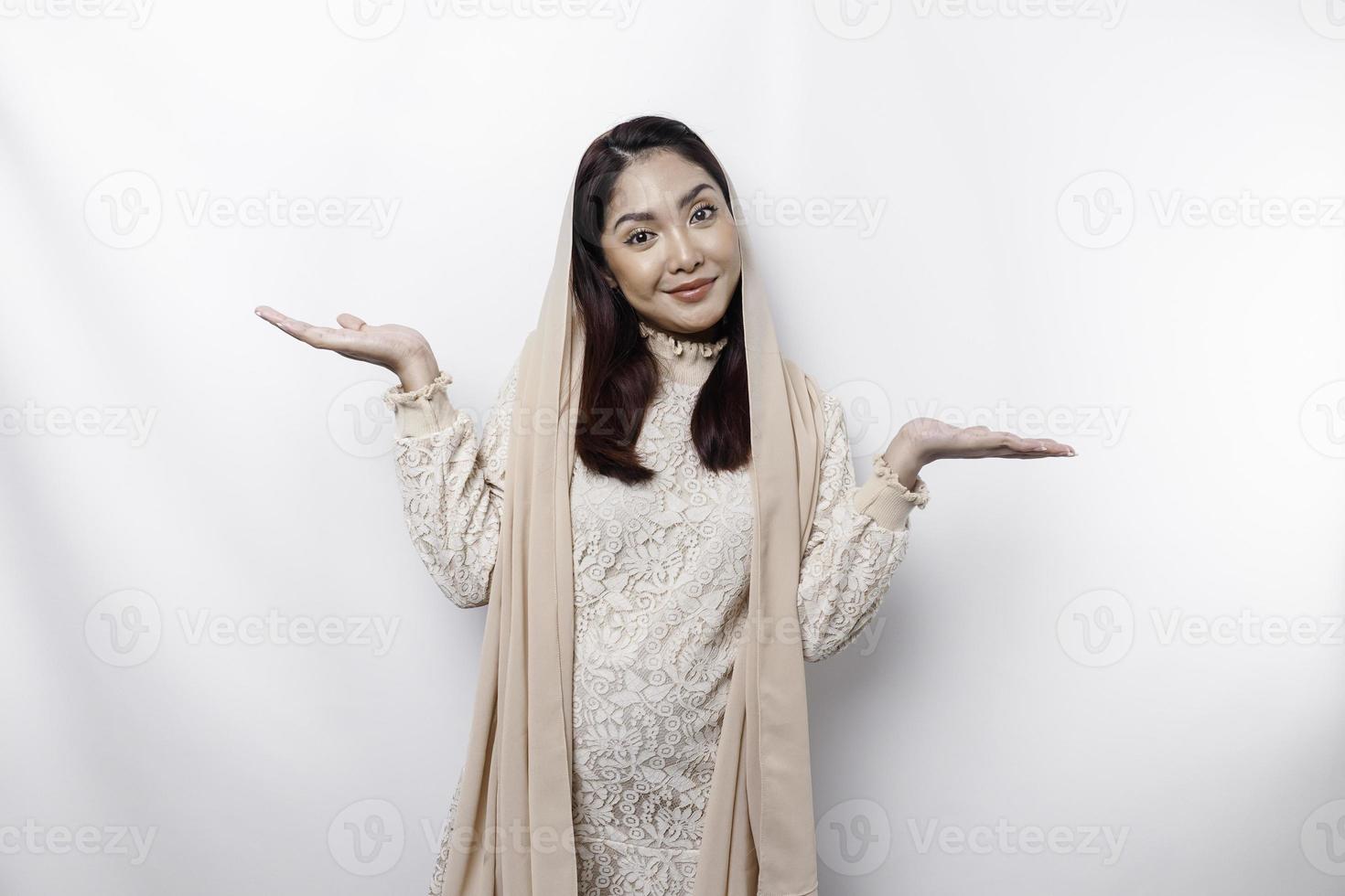 Young Asian Muslim woman smiling while pointing to copy space beside her photo