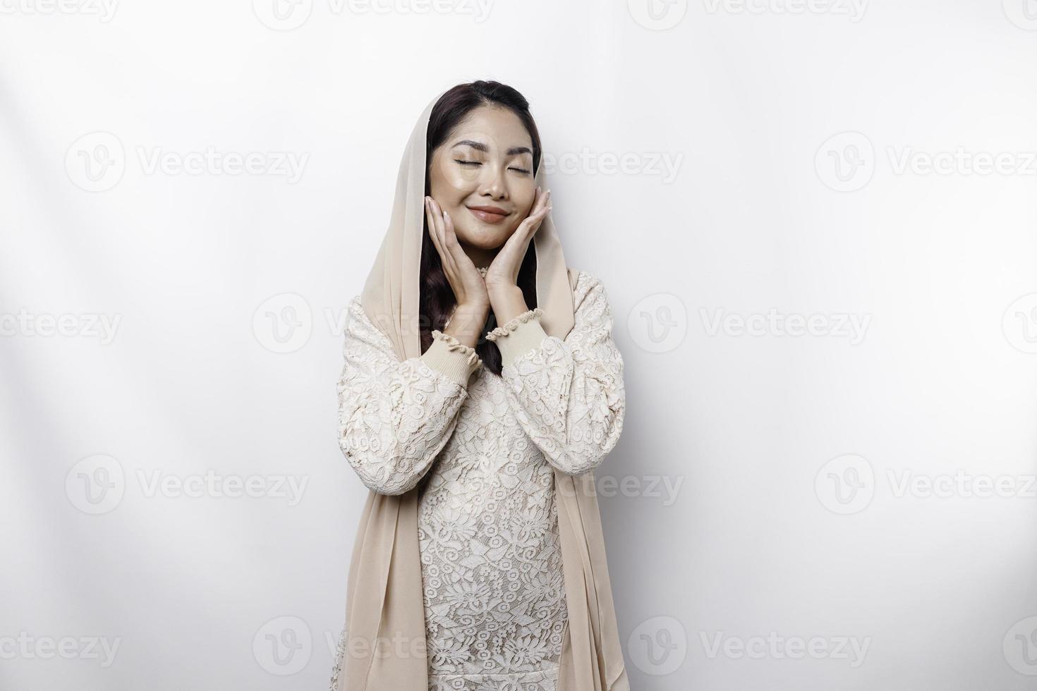 Young Asian Muslim woman wearing headscarf smiling to the camera, isolated by white background photo