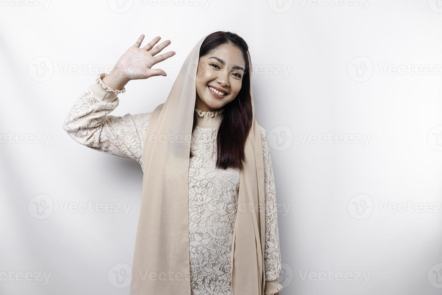 retrato de un joven hermosa asiático musulmán mujer vistiendo un Pañuelo gesticulando eid Mubarak saludo foto