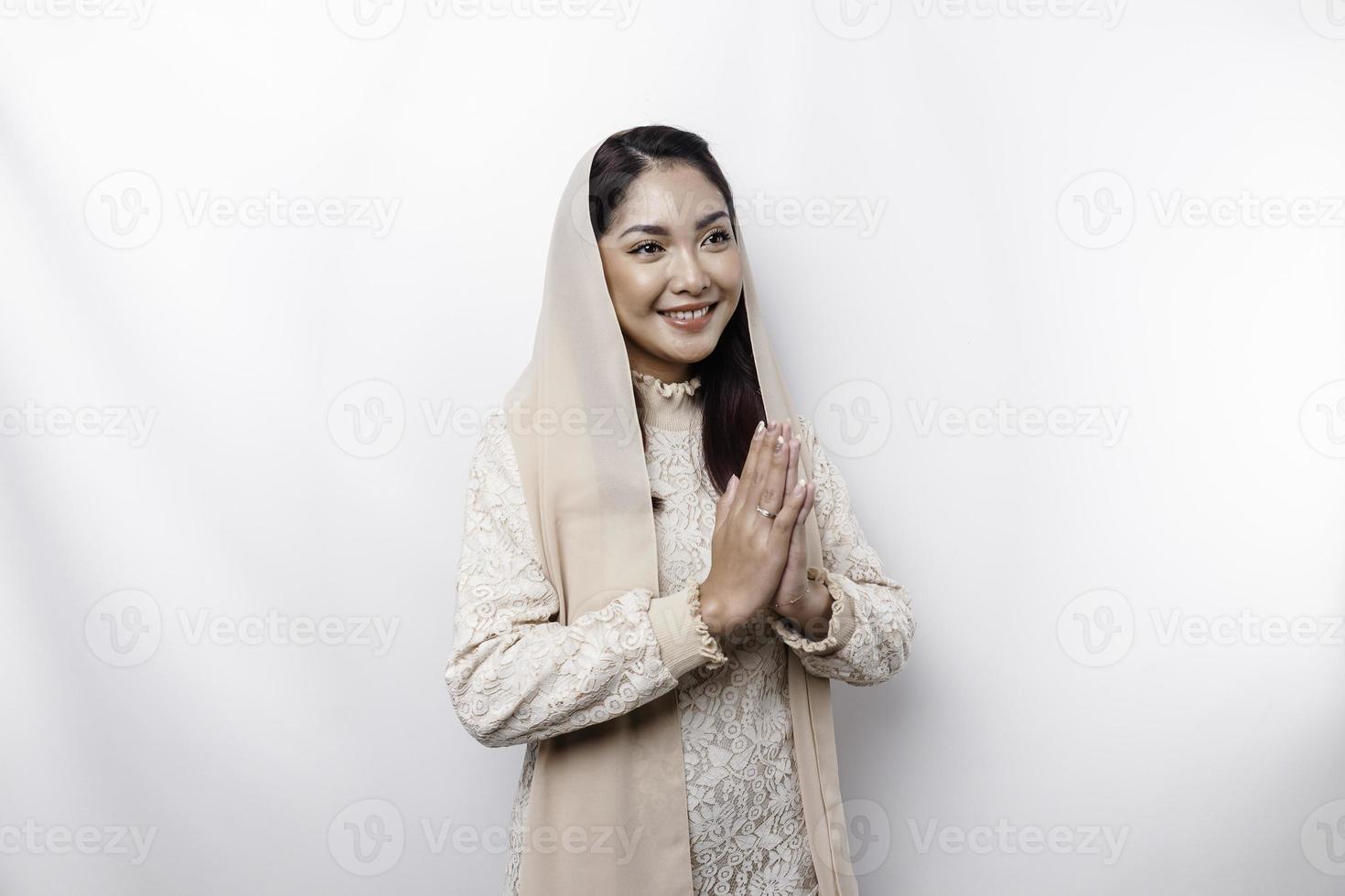 Portrait of a young beautiful Asian Muslim woman wearing a headscarf gesturing Eid Mubarak greeting photo