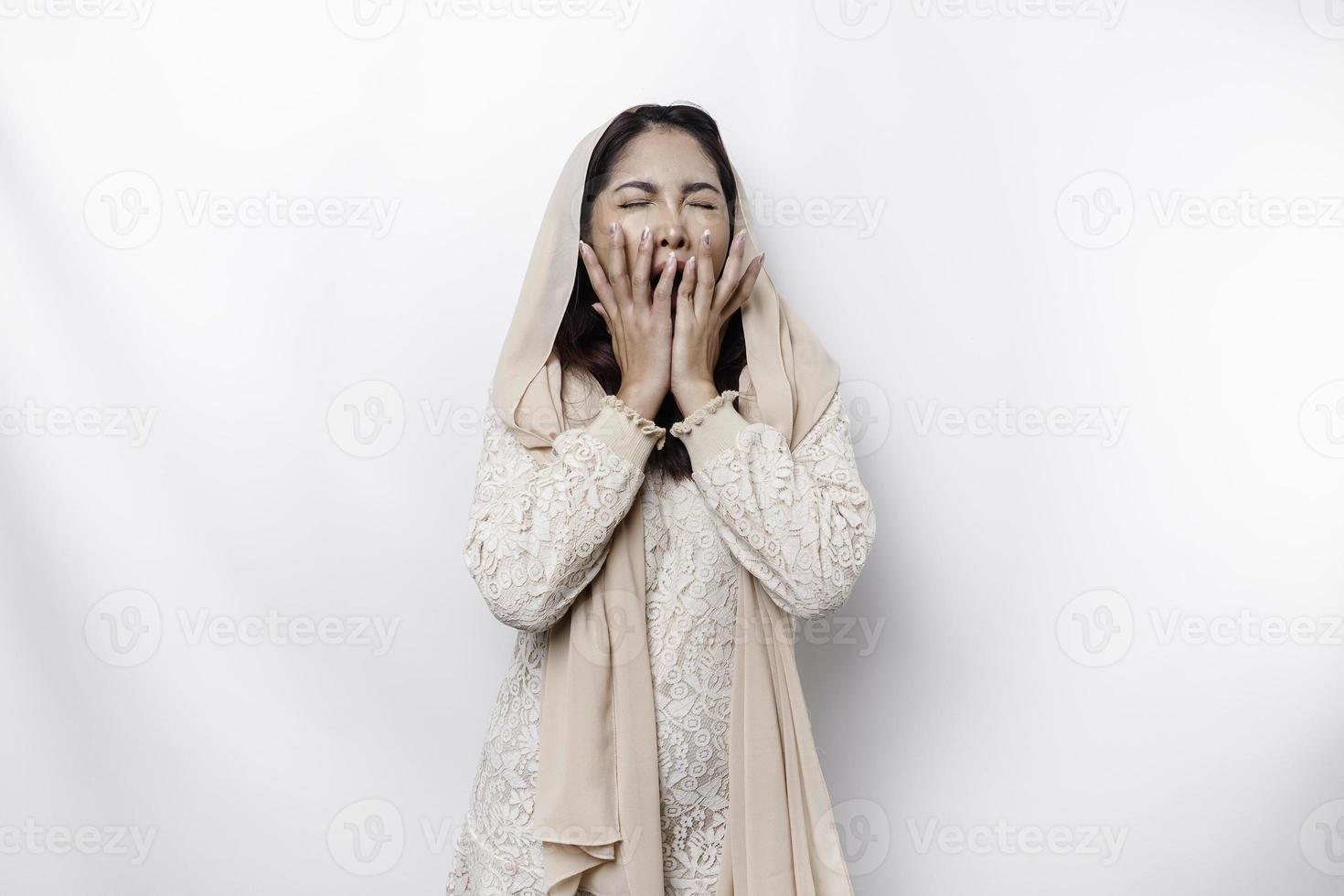 retrato de soñoliento atractivo asiático musulmán mujer vistiendo un Pañuelo, sensación cansado después noche sin dormir, bostezando, cubierta abrió boca con palma foto