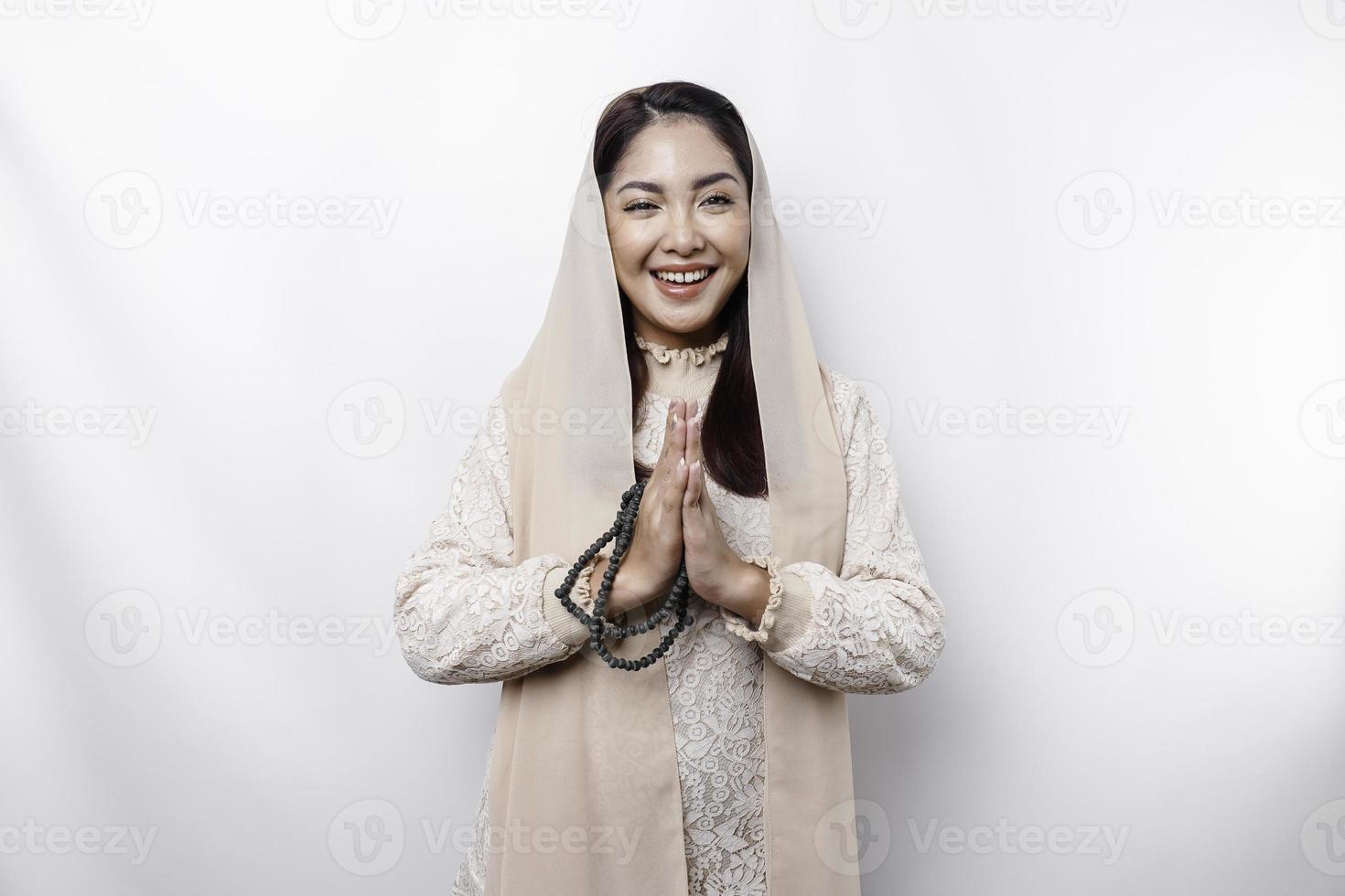 Portrait of a young beautiful Asian Muslim woman wearing a headscarf gesturing Eid Mubarak greeting photo