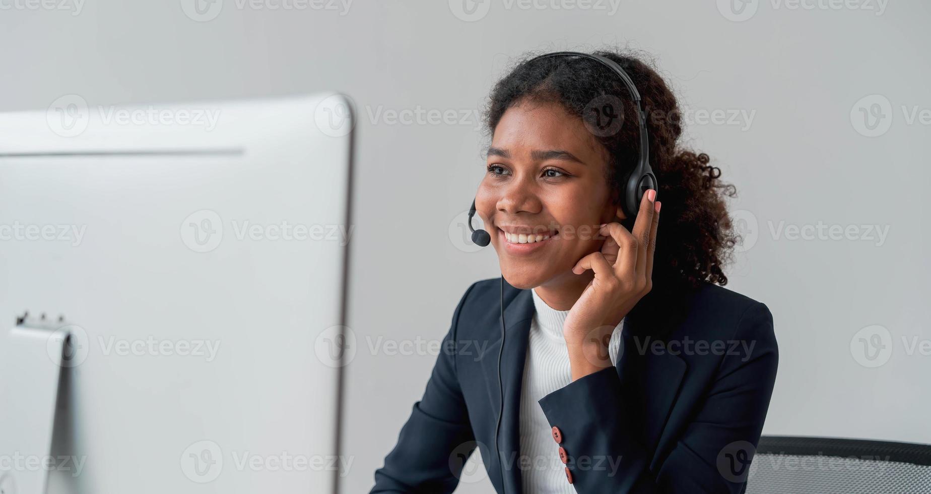 close up call center operator in wireless headset talking with customer, woman in headphones with microphone consulting client on phone in customer support service, looking at computer screen photo
