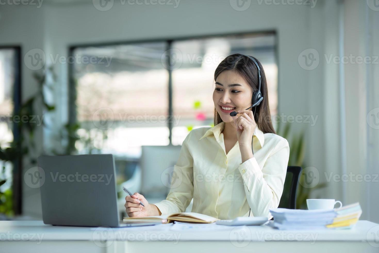 close up call center operator in wireless headset talking with customer, woman in headphones with microphone consulting client on phone in customer support service, looking at computer screen photo
