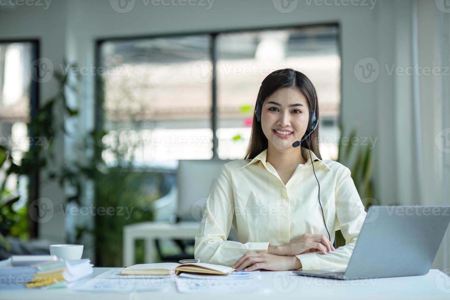 close up call center operator in wireless headset talking with customer, woman in headphones with microphone consulting client on phone in customer support service, looking at computer screen photo