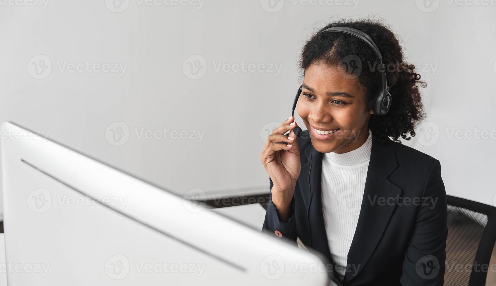 close up call center operator in wireless headset talking with customer, woman in headphones with microphone consulting client on phone in customer support service, looking at computer screen photo