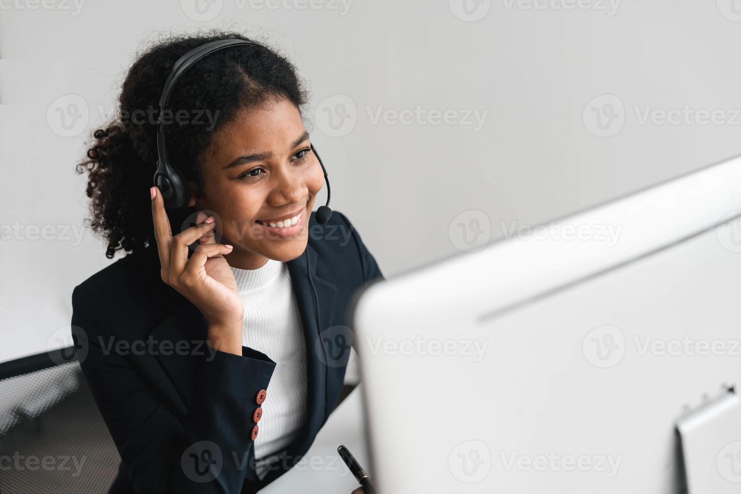 close up call center operator in wireless headset talking with customer, woman in headphones with microphone consulting client on phone in customer support service, looking at computer screen photo