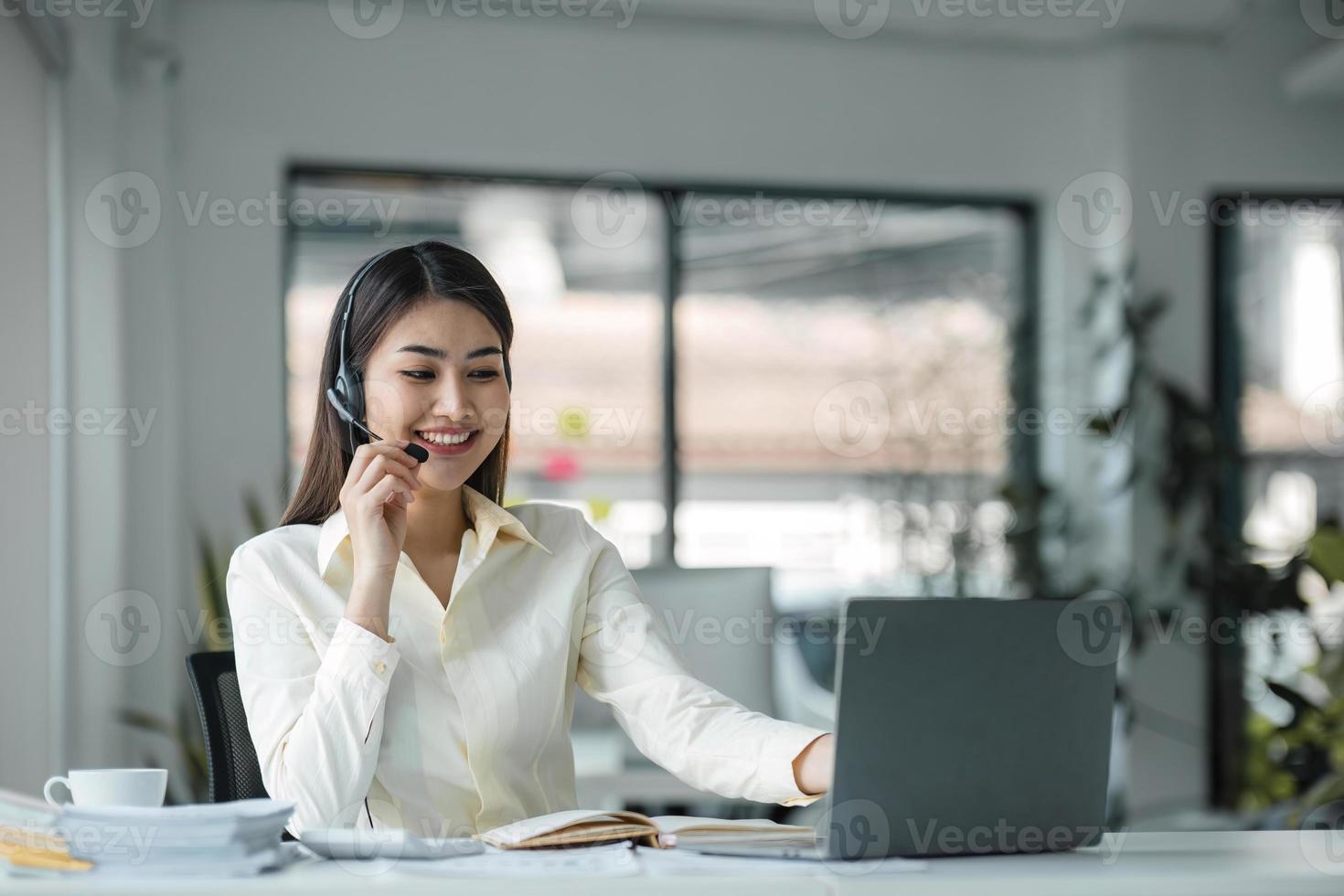 close up call center operator in wireless headset talking with customer, woman in headphones with microphone consulting client on phone in customer support service, looking at computer screen photo