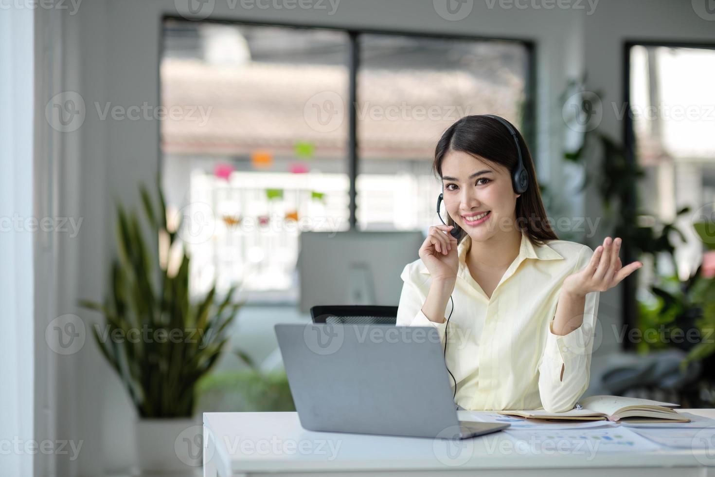 close up call center operator in wireless headset talking with customer, woman in headphones with microphone consulting client on phone in customer support service, looking at computer screen photo
