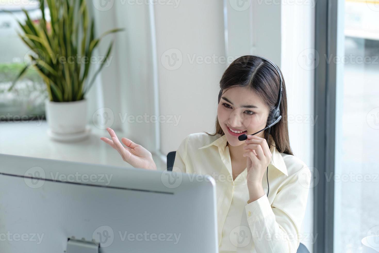 close up call center operator in wireless headset talking with customer, woman in headphones with microphone consulting client on phone in customer support service, looking at computer screen photo