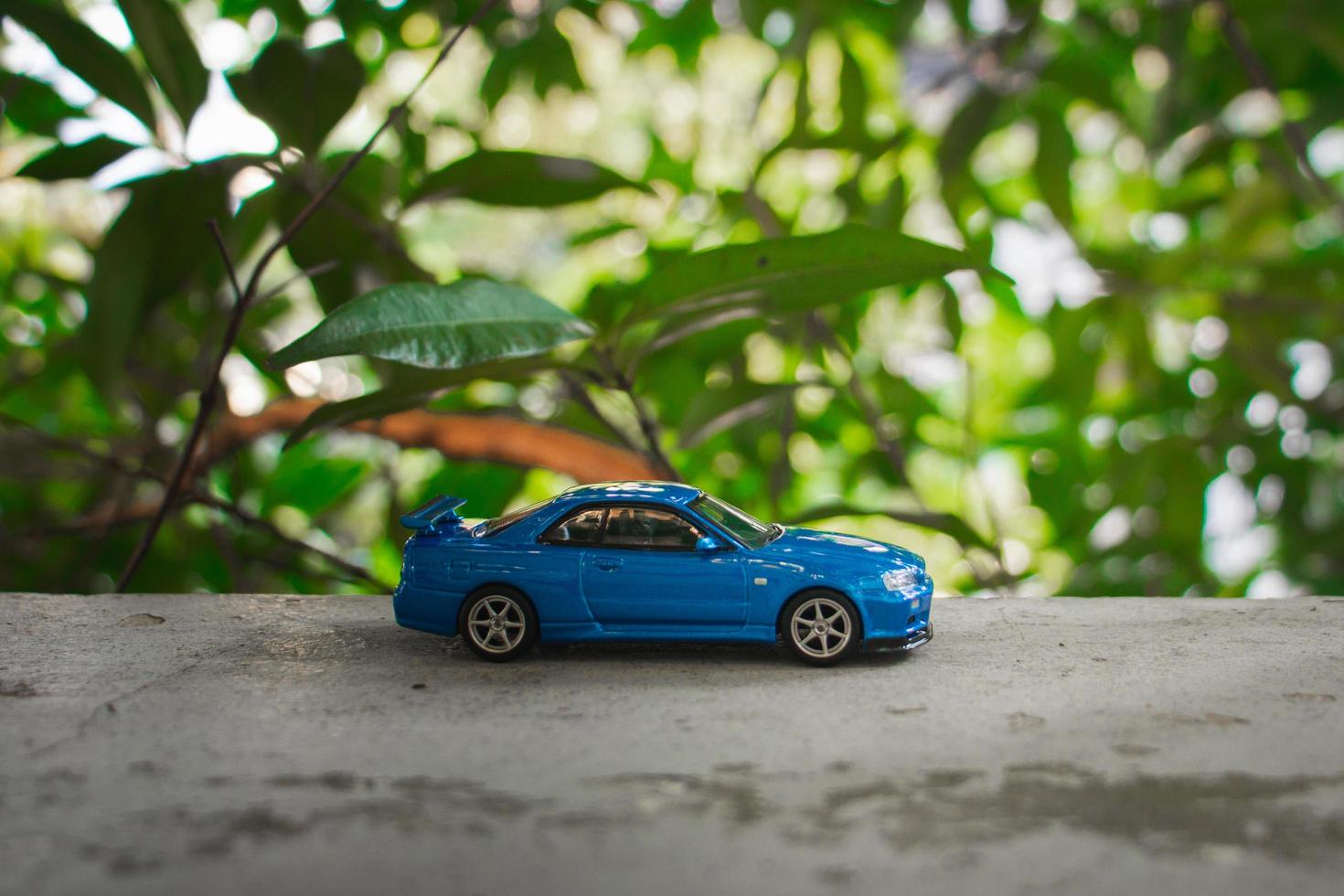 Concept for nature adventure. After some edits, a photo of blue toy car placed near a tree.