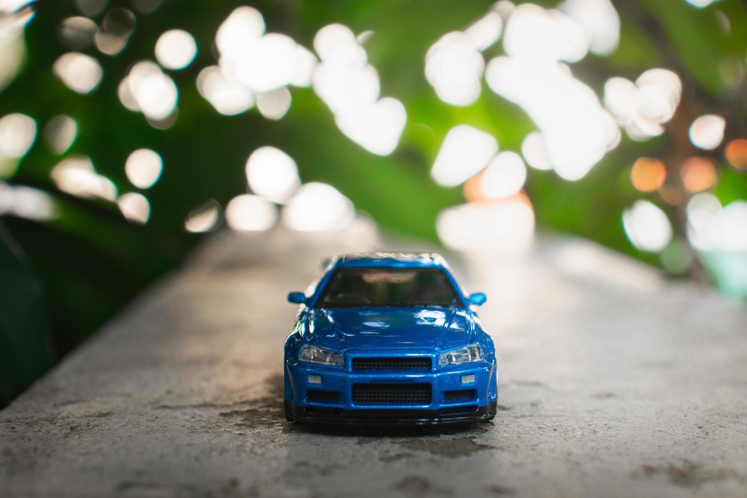 Concept for nature adventure. After some edits, a photo of blue toy car placed near a tree.