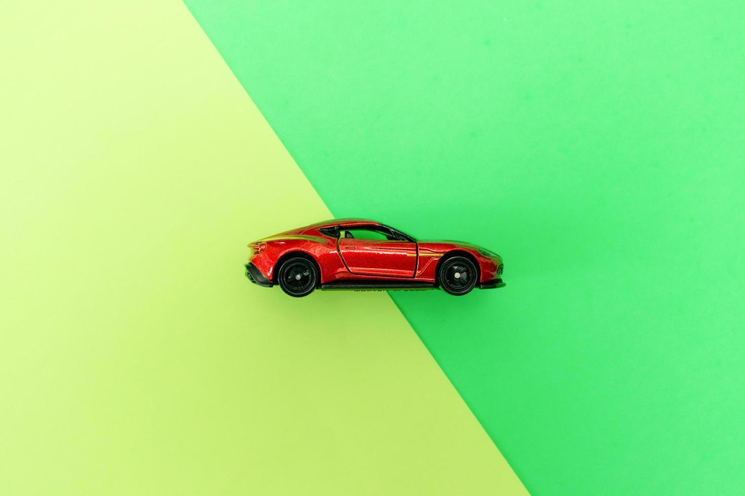 Red toy car isolated on two color background paper, after some edits. photo