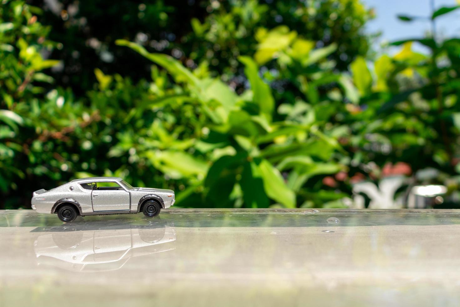 Bogor, Indonesia, March 18th, 2023 - Concept for nature and adventure with your car. Toy of old Nissan Skyline 2000 GT-R placed at the edge of glass rooftop, after some edits. photo