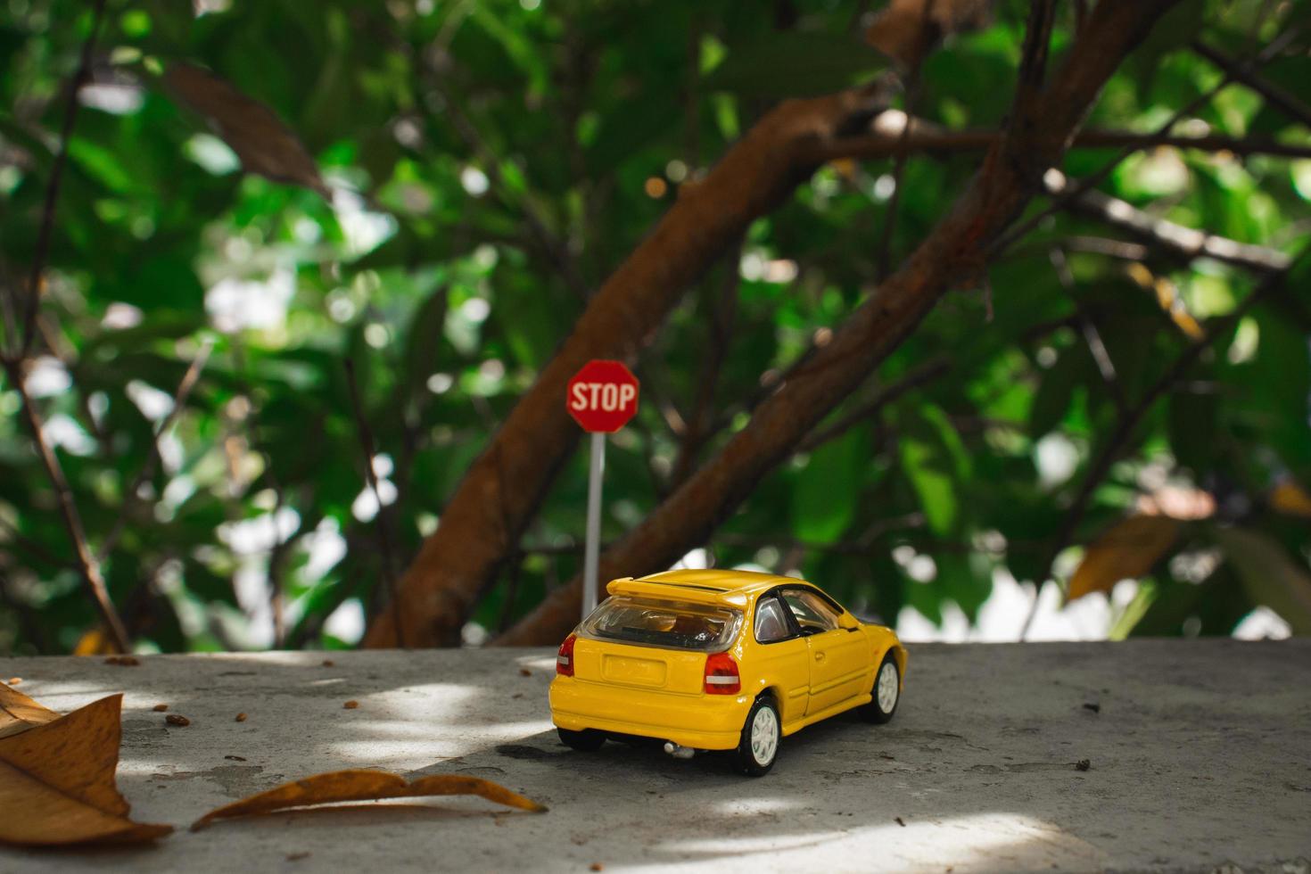 un foto de un amarillo juguete coche Satisface un detener firmar, después algunos ediciones