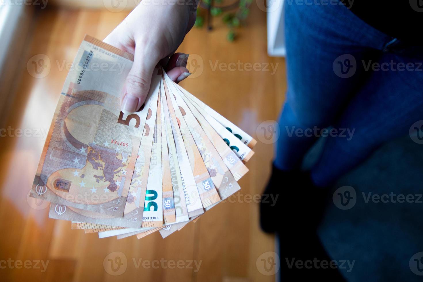 Woman's hand holding a fan of euro banknotes on a black background photo