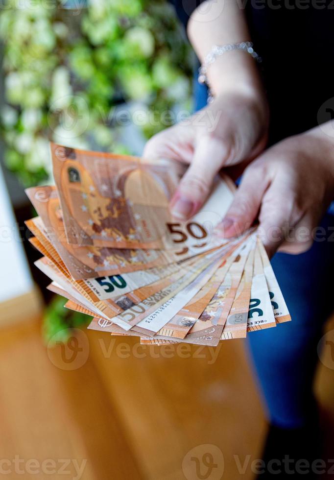 mujer mano participación un ventilador de euro billetes en un negro antecedentes foto