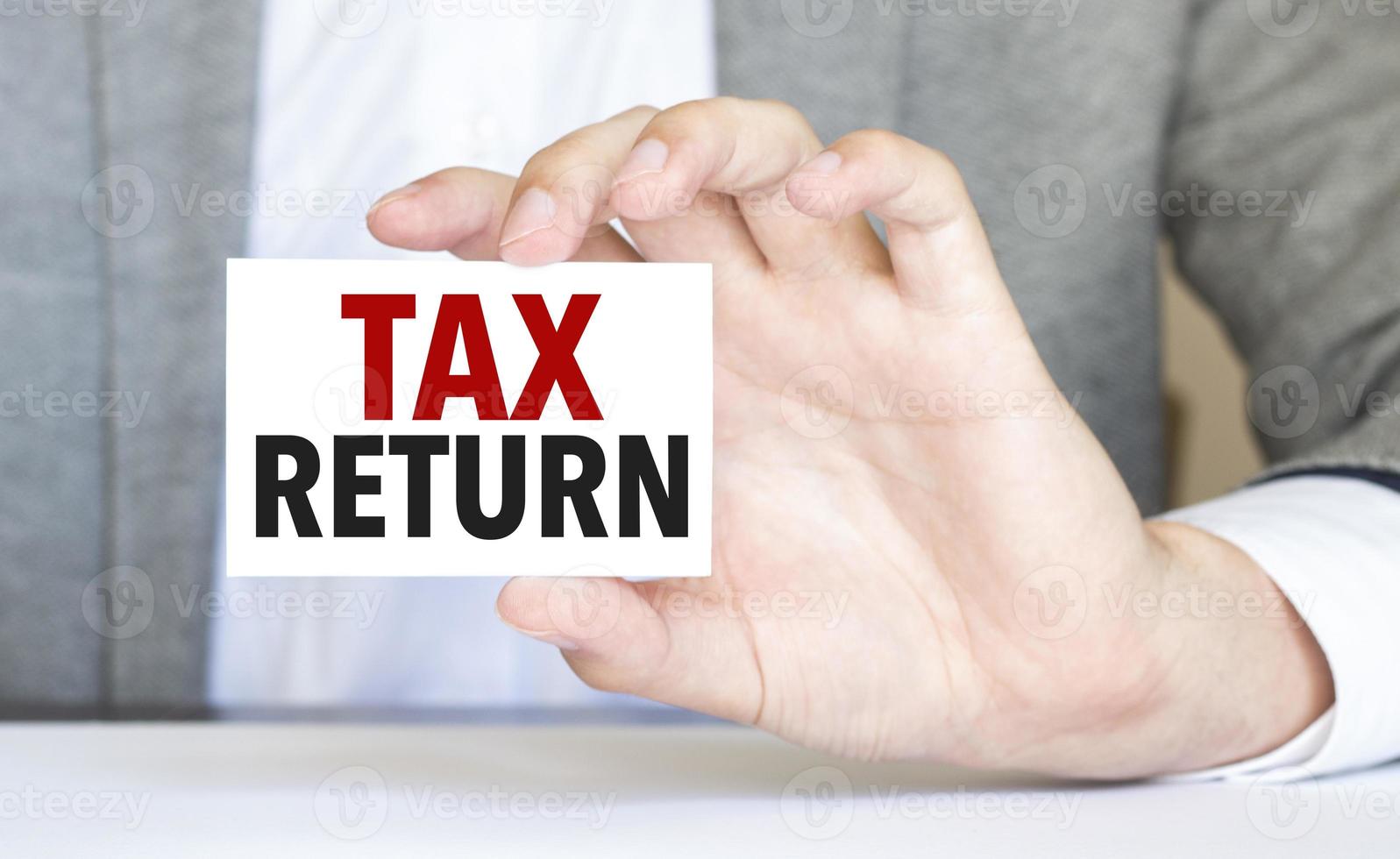 man's hand holding paper sheet with tax return words photo
