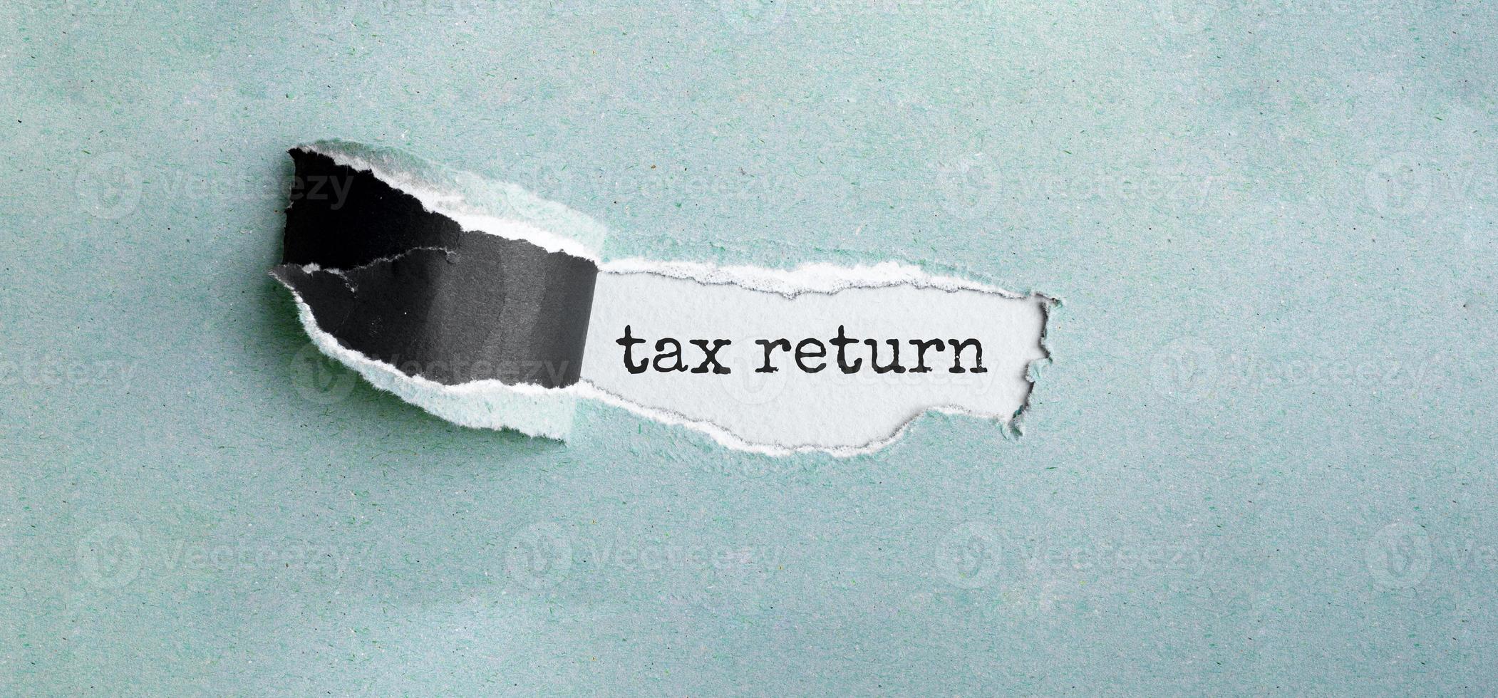 The text tax return appearing behind torn green paper photo