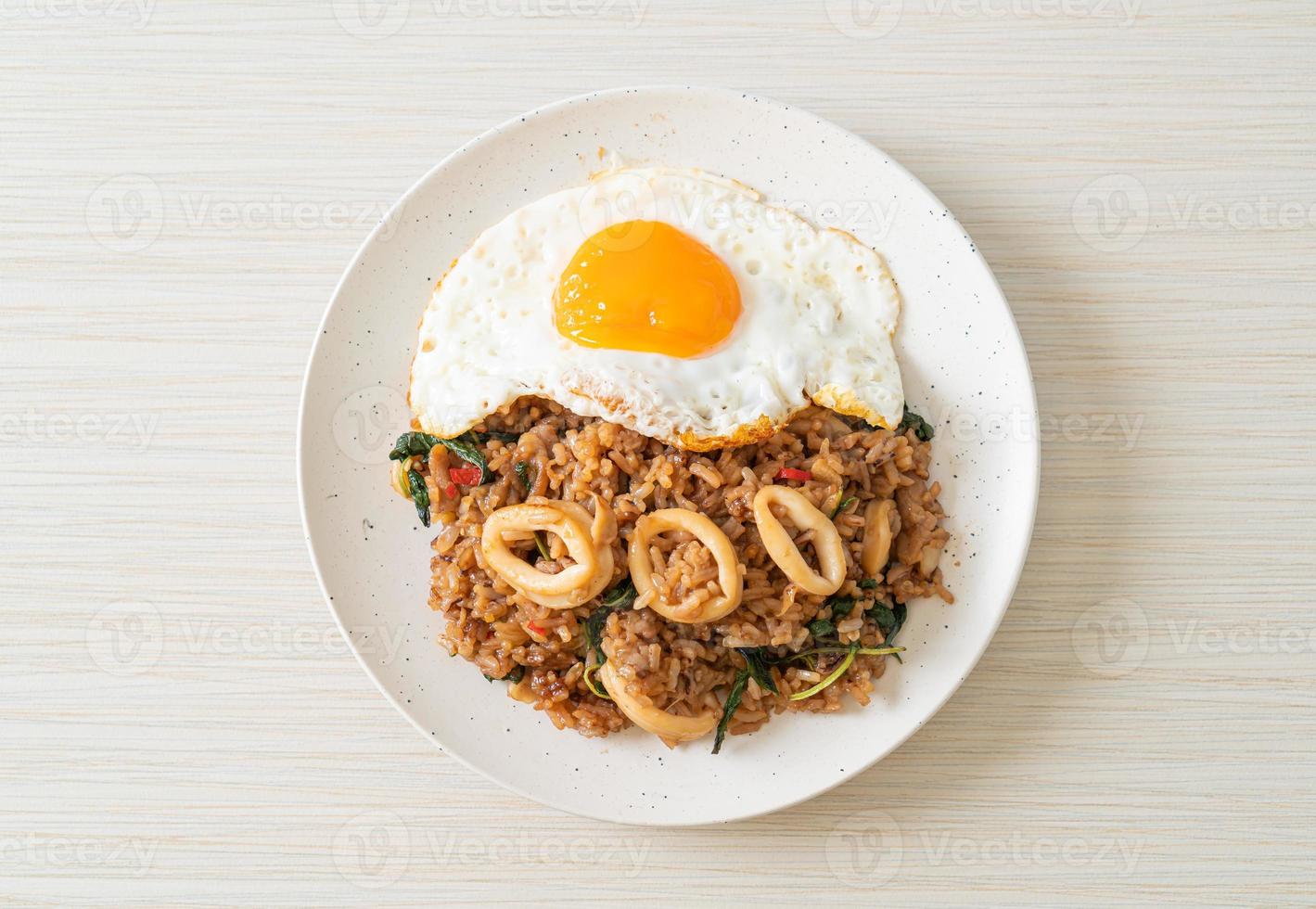 arroz frito con calamares y huevo frito cubierto de albahaca al estilo tailandés foto