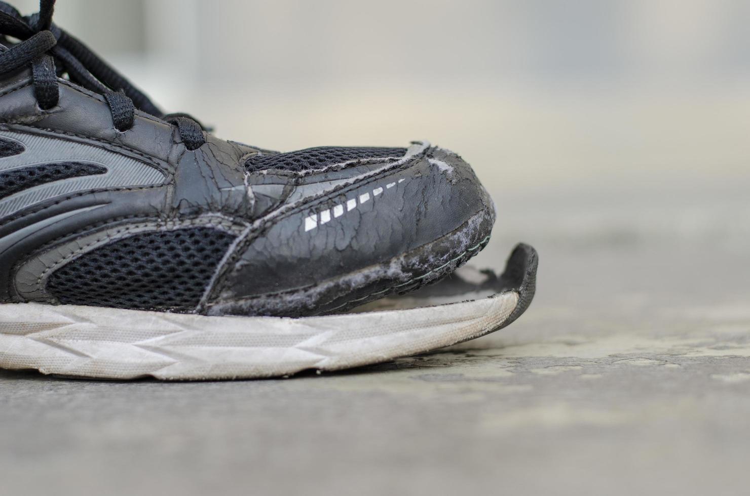 side view broken old black canvas shoes on the floor. copy space photo