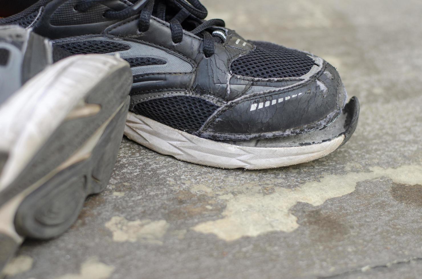 broken old black sneakers on the floor photo