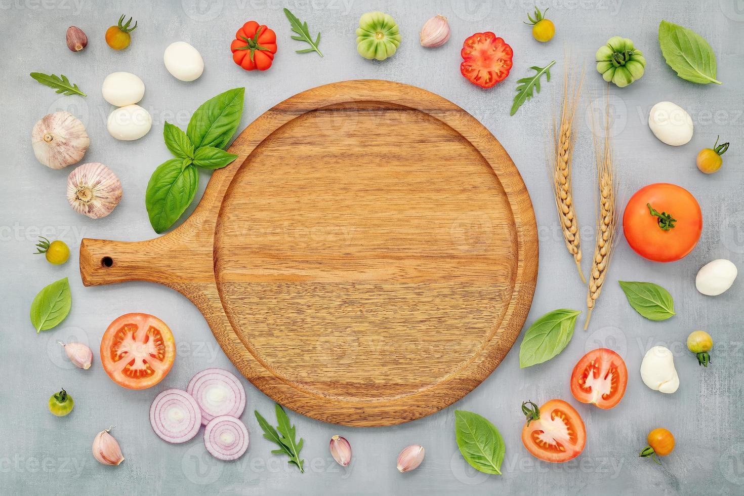 The ingredients for homemade pizza with wooden pizza tray set up on grey concrete background. top view photo