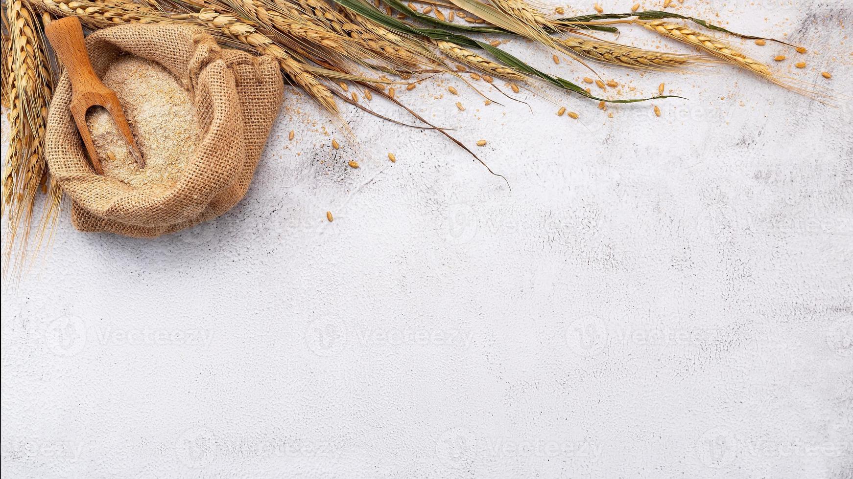 Wheat ears and wheat grains set up on white stone background. photo