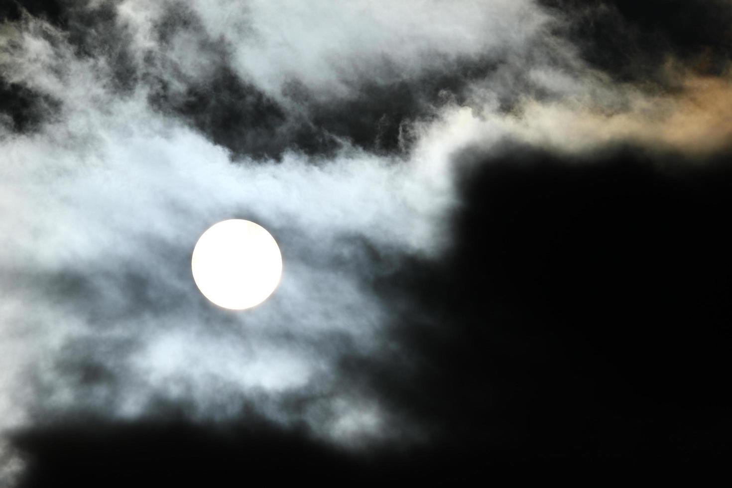 Sun disk behind backlit clouds photo