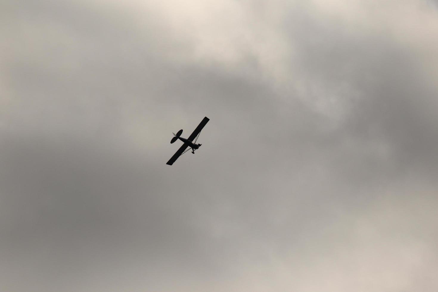 pequeño avión volador en el cielo en contra oscuro nubes foto