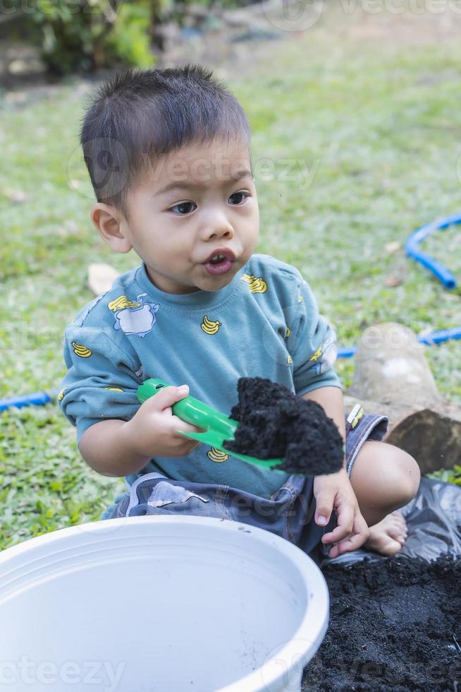 Little child shovels soil into pots to prepare plants for planting. Toddler boy digging soil for planting to Mother's little helper. Gardening. Hobbies at home horticulture. Leisure activities concept photo