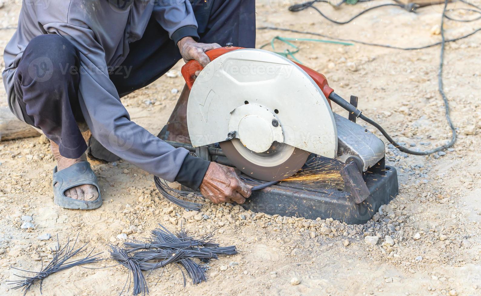 Man's hand using iron cutter in the workplace, fastening iron canopy frame with spark. Worker cutting steel with electric iron cutter. Steel cutter grinder cutting iron pipe with bright sparks. photo